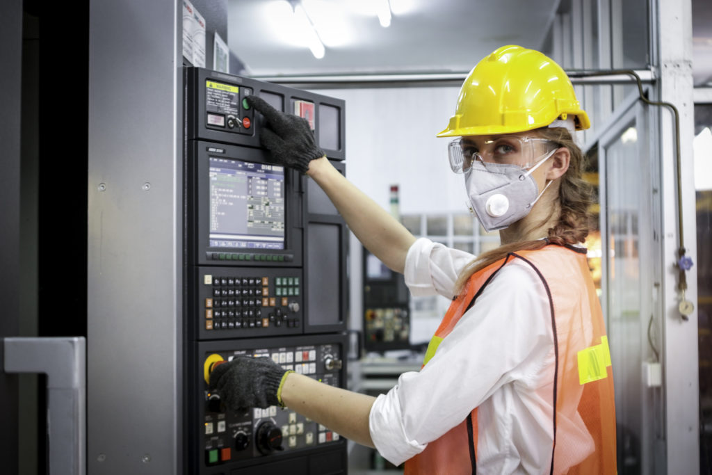 Industrial engineer worker female wearing helmet, safe glasses and mask, pointing and touching instrument panel buttons at manufacturing plant factory, young beautiful woman working in industry