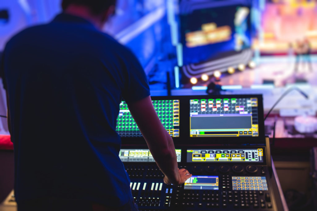 View of lighting technician operator working on mixing console workplace during live event concert on stage show broadcast, light mixer controller panel, sound technician with professional equipment